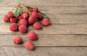 Lychees in branches with leaves over wooden table with copy space