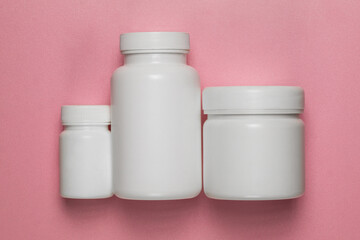 Fototapeta na wymiar Three empty plastic jars on a pink background