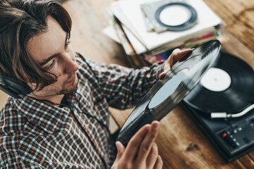 Man listening to music from vinyl record. Playing music from analog disk on turntable player....