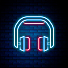 Glowing neon line Headphones icon isolated on brick wall background. Earphones. Concept for listening to music, service, communication and operator. Colorful outline concept. Vector