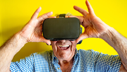 Elderly man on yellow background wearing vr while having fun