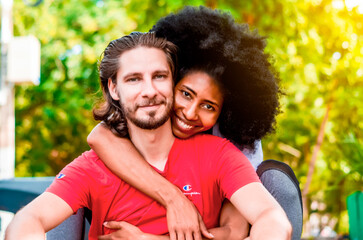 multiethnic couple hugging and happy in the park, afro girl with her partner