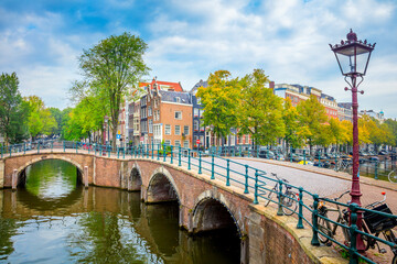 Heart of Amsterdam in one photo - leaning houses, bridges, canals, bicycles and lanterns. View of the famous old center of Amsterdam. Amsterdam, Holland, Europe