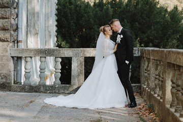 Stylish young wedding couple hugging on the porch of a rich villa in the rays of the setting...
