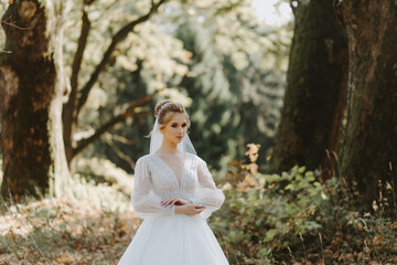 Stylish luxurious blonde bride in a white wedding dress against the backdrop of a summer sunny...
