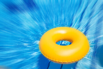 inflatable yellow inner tube floating in clear blue waters with motion blur effect