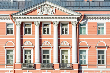 Facade of the building with pink walls with bas-relief, windows, balconies and white columns. From the series windows of St. Petersburg.