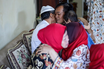 Lebaran homecoming in his hometown greet each other apologizing during the Eid. Family hug each other, parents with their children. 