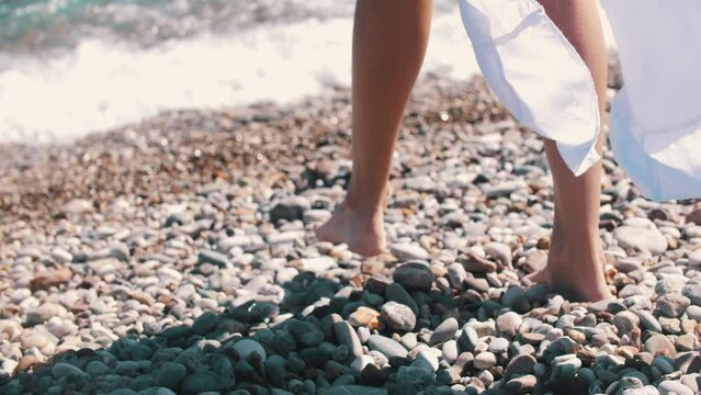 A woman walks on pebbles and walks to the sea water