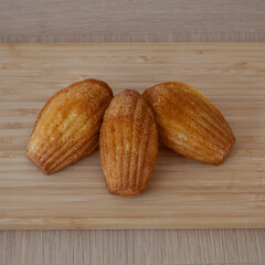 French madeleine cakes on a wooden chopping board, shot from above.