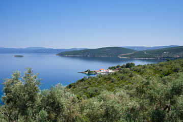 Fototapeta premium Wonderful Greek landscape, traditional house in front of a small bay and an olive grove that touches the sea. Pelion, Trikeri, Greece