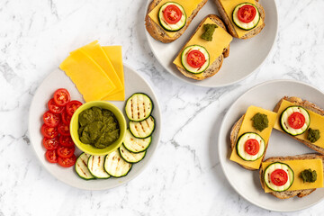 Open sandwiches with bread, cheese slices, grilled zucchini, tomato and coriander chutney. Top view.