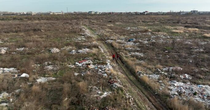 two people walking on a huge aste, garbade, dump, rubbish landill in Bucharest