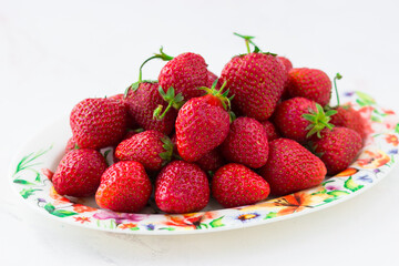 Ripe strawberries on a plate on a white background. Summer berries