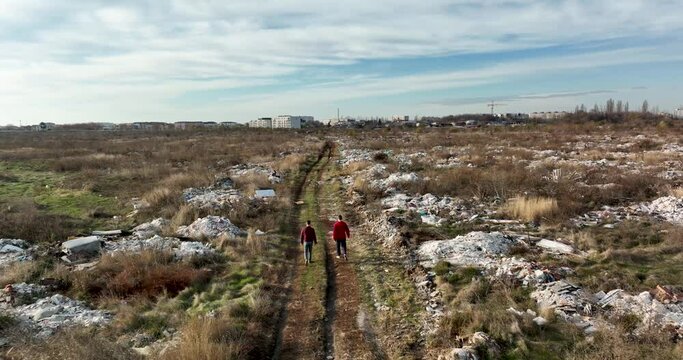 two people walking on a huge aste, garbade, dump, rubbish landill in Bucharest