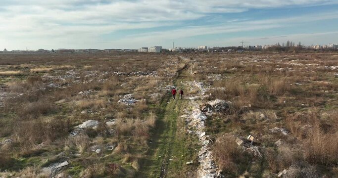 two people walking on a huge aste, garbade, dump, rubbish landill in Bucharest