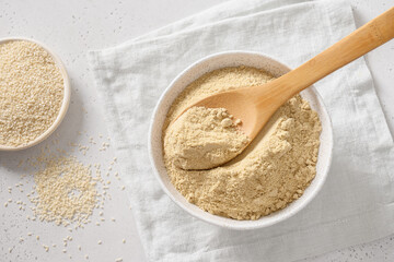 Sesame flour in wooden spoon. View from above. Good vegan source of protein, minerals, natural...