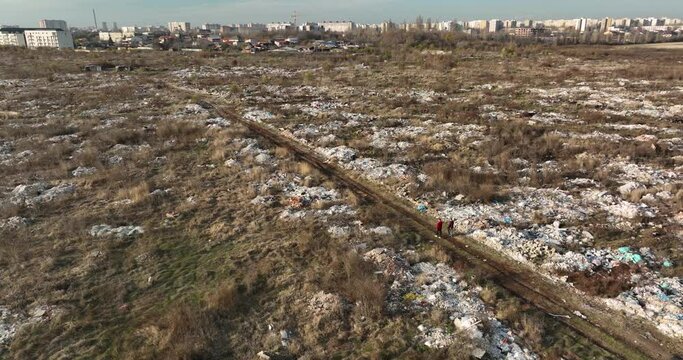 two people walking on a huge aste, garbade, dump, rubbish landill in Bucharest