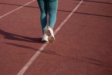 Detalle de pies de mujer corriendo en una pista atlética. Concepto de deportes y gente.