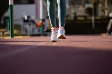Detalle de pies de mujer corriendo en una pista atlética. Concepto de deportes y gente.