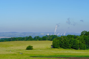 Green scenery with conventional coal power plant in the background