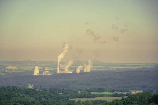 Coal energy, fossil fuel power generation behind the rows of trees of the forest