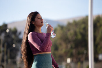 Mujer hidratándose después de ejercitarse. Concepto de deportes y estilo de vida.