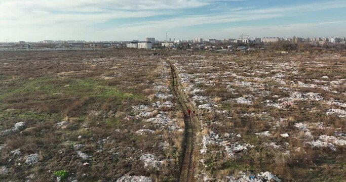two people walking on a huge aste, garbade, dump, rubbish landill in Bucharest