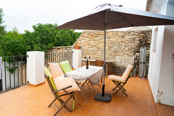 outdoor wooden table and chairs with umbrella placed next to the balcony