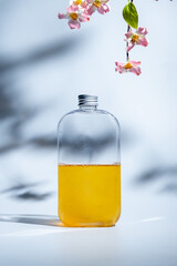 drink in a glass bottle on white background with hard or Harsh shadows and sunlight of leaves tree branch falling on wall. modern and minimal product design. cold refreshment beverage.