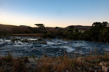 A standing man points to the side of a beautiful river.