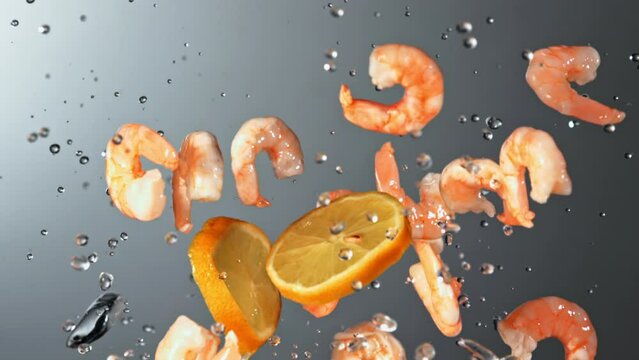 Shrimp with pieces of ice and splashes of water fly up and rotate in flight. On a gray background. Filmed is slow motion 1000 fps.