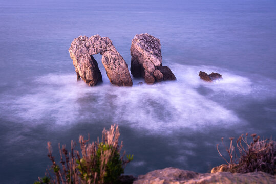Long exposure view of the beautiful seascape with the spectacular rock formations near the coast in the Cantabrian sea from the cliff edge, Urro in Costa Quebrada at sunset, Liencres, Cantabria, Spain