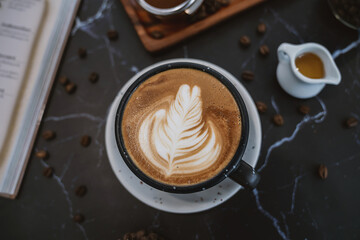 Background banner cup of honey cappuccino with latte art on wooden top view, flat lay. Black ceramic cup of Latte coffee dark vintage style.
