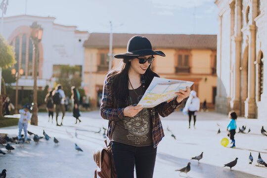 Mujer caminando por una plaza de Sudam&eacute;rica con un plano en la mano. Concepto de viajes y turismo.
