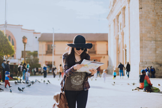 Mujer caminando por una plaza de Sudam&eacute;rica con un plano en la mano. Concepto de viajes y turismo.