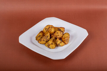 Batata rústica em prato quadrado branco isolada com fundo marrom