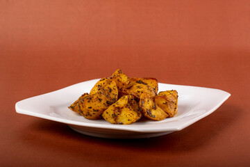 Batata rústica em prato quadrado branco isolada com fundo marrom