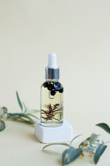 A cosmetic bottle with body oil stands on a rise, surrounded by fresh leaves. - 512852340