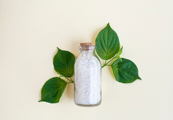 A bottle of sea salt for the bath and a few green leaves. Top view. - 512852349