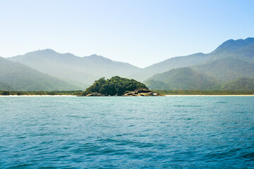 Small rocky isolated island between two beaches with mountains in the background. Praia do Leste...