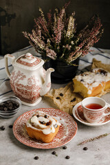 Cinnabon roll with great cream on it, with a tea cup on background and a beautiful background