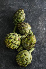 Fototapeta premium Fresh Artichoke on black background. Raw Artichok closeup