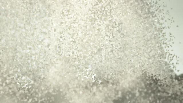 Sugar rises up and falls down. On a white background. The texture of sugar. Filmed on a high-speed camera at 1000 fps.