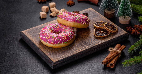 A beautiful doughnut with pink glaze and colored sprinkle on a christmas table