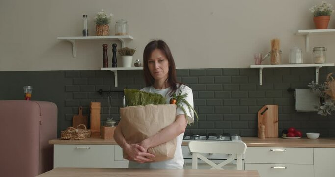 Woman holding paper bag with groceries and drink wine from cup from bag
