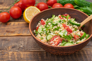 Tabbouleh salad is a traditional Middle Eastern or Arabic cuisine. Vegetarian salad with bulgur, tomatoes, cucumbers, parsley, copy space; place for text.