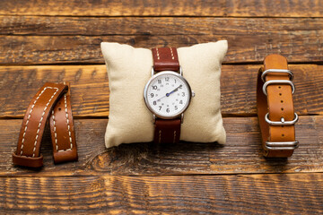A set of watches and handmade leather straps for them. Stylish, vintage replacement watch straps made of genuine leather and watches on a wooden background. - obrazy, fototapety, plakaty