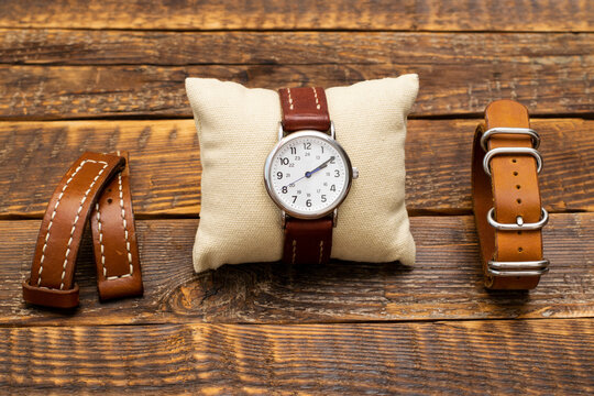 A set of watches and handmade leather straps for them. Stylish, vintage replacement watch straps made of genuine leather and watches on a wooden background.