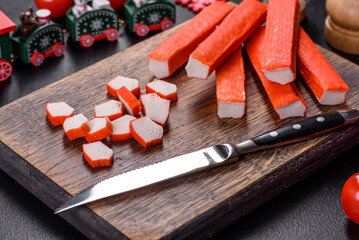 Crab sticks on a cutting Board with a knife. On a black christmas table